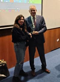 male presenting a glass trophy-style award to female student